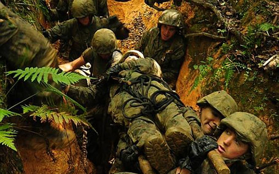 Marines carry a simulated casualty on a stretcher they made from sapling trees and their utility blouses. The Marines had to carry the stretcher along the muddy, slippery trail and were not allowed to put it down.  The casualty is a Marine chosen by a Jungle Warfare Training Center instructor and is generally one of the heaviest on the team.