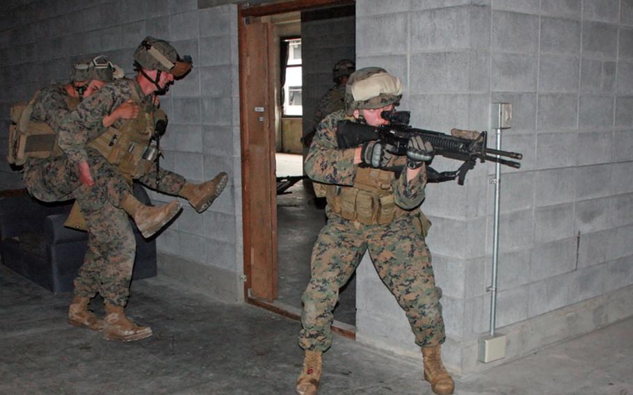 A Marine stands guard while another carries an injured team member during Company C, 3rd Reconnaissance Battalion&#39;s Military Operation in Urban Terrain training at Camp Fuji, Wednesday.