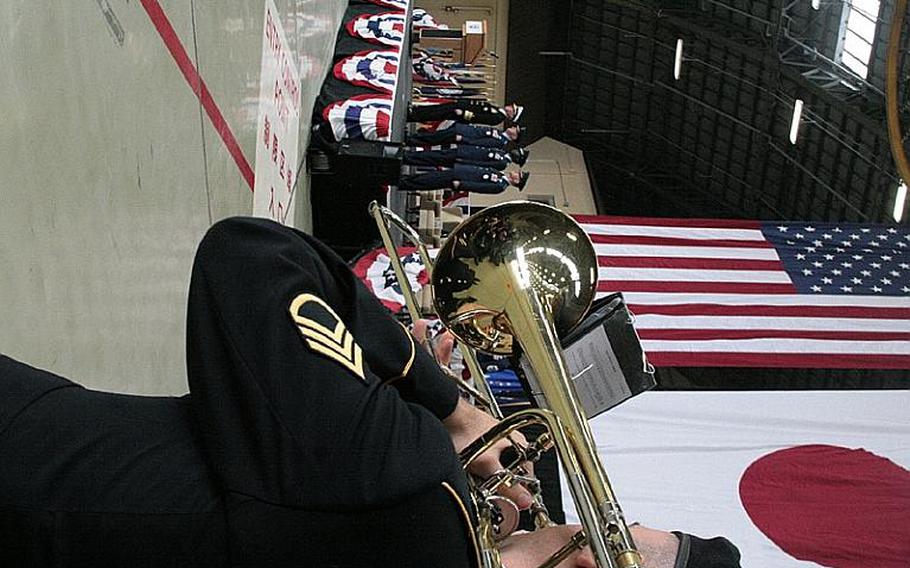 A member of the 296th U.S. Army Band plays as (from left to right) Adm.  Robert Willard, commander, U.S. Pacific Command, Gen. Gary North, commander, Pacific Air Forces, Lt. Gen. Edward Rice, outgoing U.S. Forces Japan commander, and Lt. Gen. Burton Field, incoming USFJ commander, take the stage Monday during a USFJ change of command ceremony at Yokota Air Base.