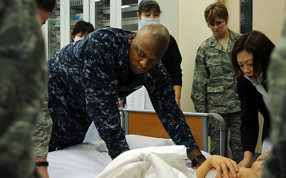 Petty Officer 2nd Class Chamunorwa Chimhau helps move a patient at the new Misawa City Hospital. Misawa City opened its new hospital last week.