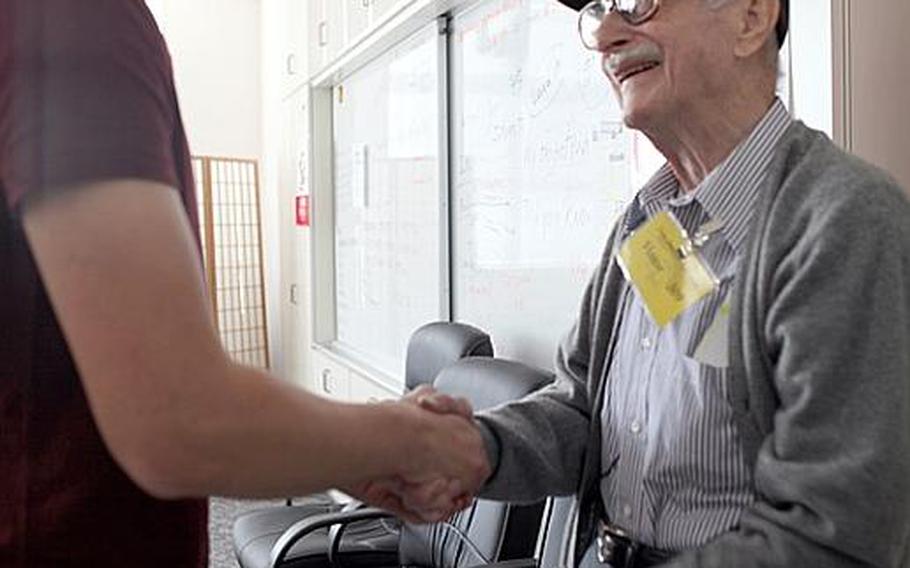 Mike Jurkoic, a retired World War II veteran, shakes hands with a Zama American High School student after sharing experiences from his military service during a Veterans Day event Tuesday at the school.