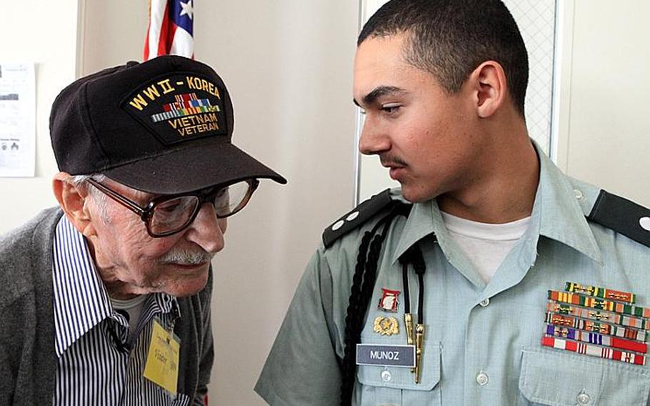 Junior Cadet 1st Lt. Michael Munoz, with the 8th Brigade Junior ROTC, chats Tuesday with retired World War II veteran Mike Jurkoic at Zama American High School. Jurkoic was guest speaker for a Veterans Day event at the school.