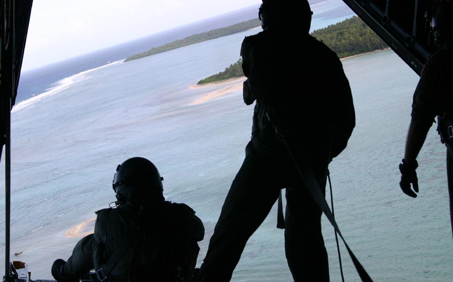 Tech. Sgt. Walter Fujioka, left, and Master Sgt. Kevin Saquilan watch islanders retrieve the boxes they just dropped out of their C-130 during the 2005 Christmas Drop out of Andersen Air Force Base, Guam. The plane was crewed by members of the 36th Airlift Squadron of the 374th Airlift Wing based in Yokota Air Base, Japan.