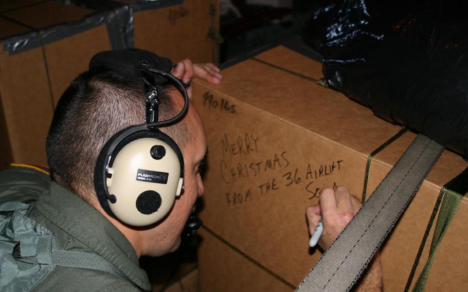 Master Sgt. Kevin Saquilan, a loadmaster, writes a Christmas message on one of the boxes to be dropped to residents of the outer islands of Chuuk State on the Federated States of Micronesia. The box later was parachuted as part of the 2005 Christmas Drop out of Andersen Air Force Base, Guam, from a C-130 transport plane. The C-130 was crewed by members of the 36th Airlift Squadron of the 374th Airlift Wing based in Yokota Air Base, Japan.
