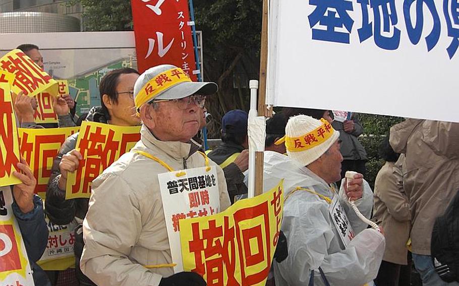 Kazuo Nakamoto, 70, of Naha holds a sign that reads "Drop (the Henoko plan)" during a protest Friday in front of the Okinawa prefectural government office. About 500 people showed up to protest Prime Minister Naoto Kan's visit to the island.