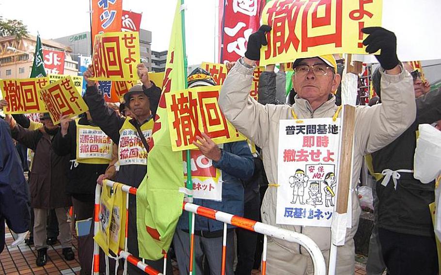 Kazuo Nakamoto, foreground, 70, of Naha holds a sign that reads "Drop (the Henoko plan)." About 500 people gathered Friday in front of the Okinawa prefectural government office to protest Prime Minister Naoto Kan's visit to the island. 