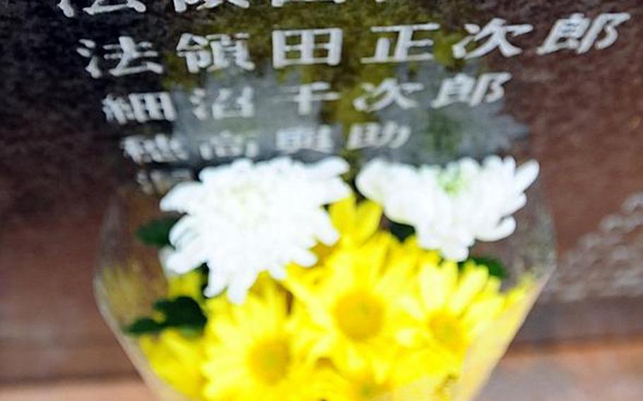 A bouquet of chrysanthemums was placed at the bottom of a mural bearing the name of Army Sgt. Keijiro Hojo (top name), who owned the wallet that Durl Gibbs flew halfway around the world to return.