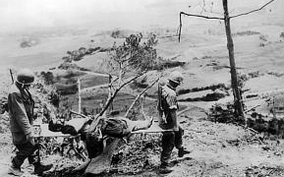 Two soldiers from E Company, 381st Infantry Regiment evacuate an injured Okinawa civilian to the rear on June 13, 1945.