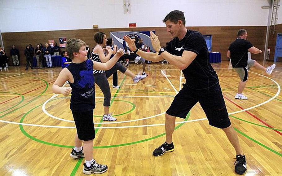 Nine-year-old Tristan McCoy receives some pointers from Robert Hudgens, an instructor of the 'P90X' fitness program during a demonstration Wednesday at Yokota Air Base. Hudgens assisted developer and star of the home fitness videos, Tony Horton, as part of Horton's weeklong tour of military bases in the Pacific.