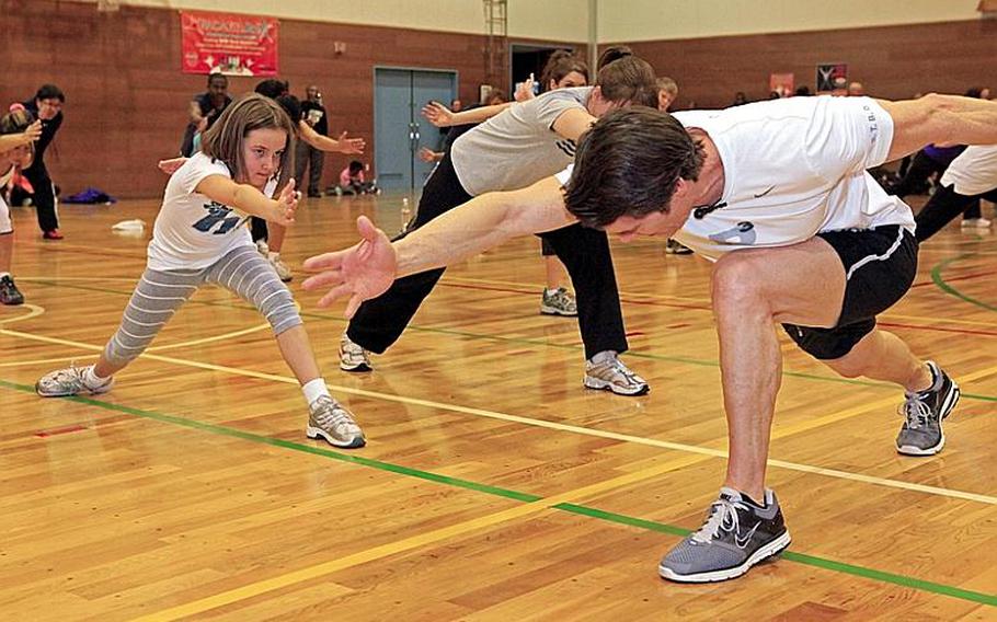 Aryn Hanna, 8, gets instruction Wednesday on how to do part of the 'P90X' fitness program by Tony Horton, right, a developer and star of the 'extreme home fitness' program, at Yokota Air Base, Japan.
