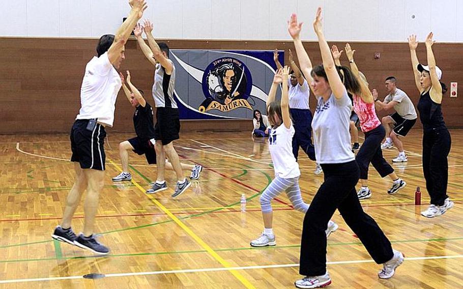 Fitness guru Tony Horton, left, a developer and star of the 'P90X' home fitness program, leads military personnel and families in exercises at Yokota Air Base, Japan.