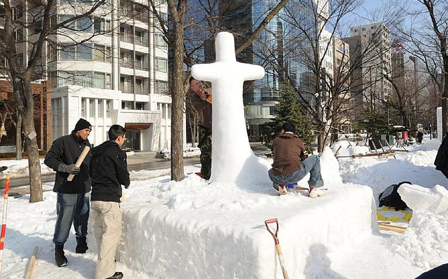 U.S. sailors and members of the Japan Ground Self-Defense Force work Friday to rebuild a snow sculpture that collapsed in unseasonably warm weather on Thursday at the Sapporo Snow Festival.