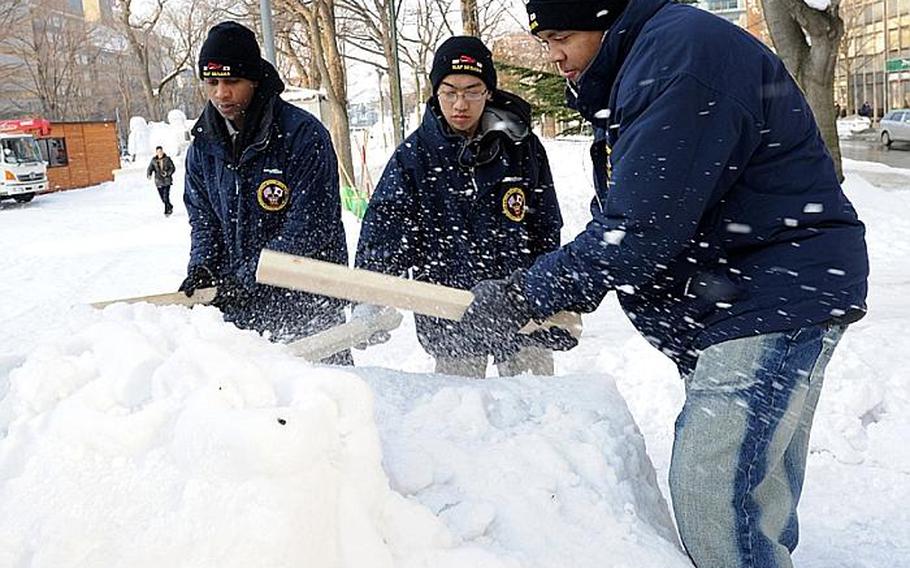 U.S. sailors work Friday to rebuild a snow sculpture that collapsed the day before in unseasonably warm weather at the Sapporo Snow Festival.