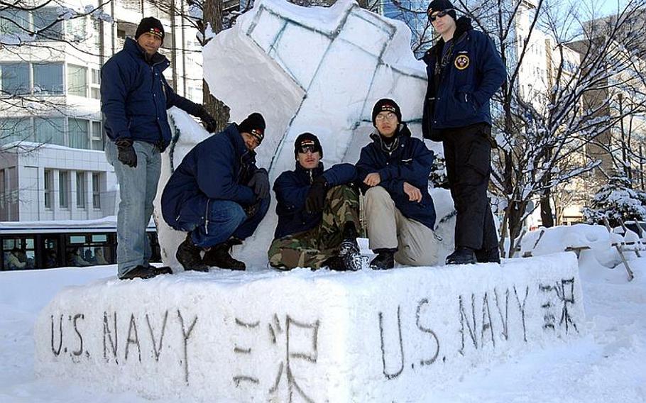 U.S. sailors from Misawa Air Base, Japan, pose on their snow sculpture Wednesday at the 62nd Sapporo Snow Festival. From left, are: Petty Officer 3rd Class Draylon Polk, Petty Officer 2nd Class Tywan Ballard, Chief Petty Officer Billy Knox, Airman Johnny Tran and Petty Officer 3rd Class Dan Grimes. The anchor melted and collapsed Thursday, leaving the team scrambling Friday to rebuild the sculpture.