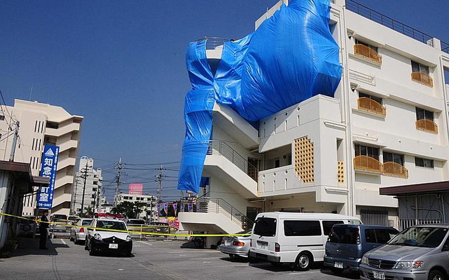 Japanese police guard a Chatan building shrouded in blue tarp after Tech. Sgt. Curtis Eccleston was found dead there in his 4th floor apartment.