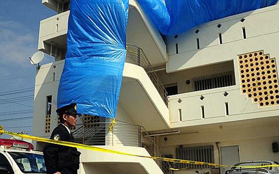 Japanese police guard the apartment building in Chatan near Camp Lester, where Tech. Sgt. Curtis Eccleston was found dead Sunday. Investigators shrouded the building in blue tarp to obscure public view.