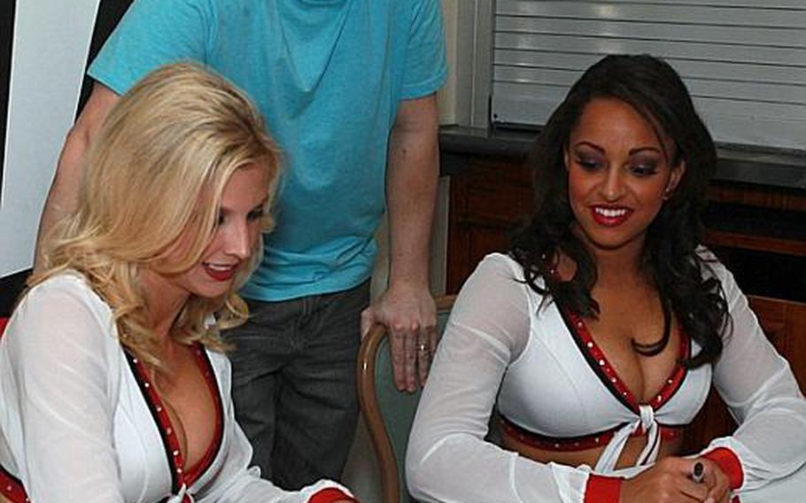 Tech Sgt. Frank Uecker, 374th Civil Engineer Squadron, gets Arizona Cardinals Cheerleaders Marcie (left) and Dionna's autograph at Yokota Air Base during halftime of the Super Bowl on Monday.