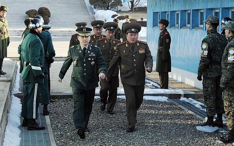 North Korean military officials, accompanied by a South Korean officer and flanked by South Korean troops, march across the North-South Korea border for a second day of talks. The meetings are being held to set a date and agenda for future higher-level military talks about the sinking of a South Korean warship last spring and North Korea´s bombing of a South Korean island in November.