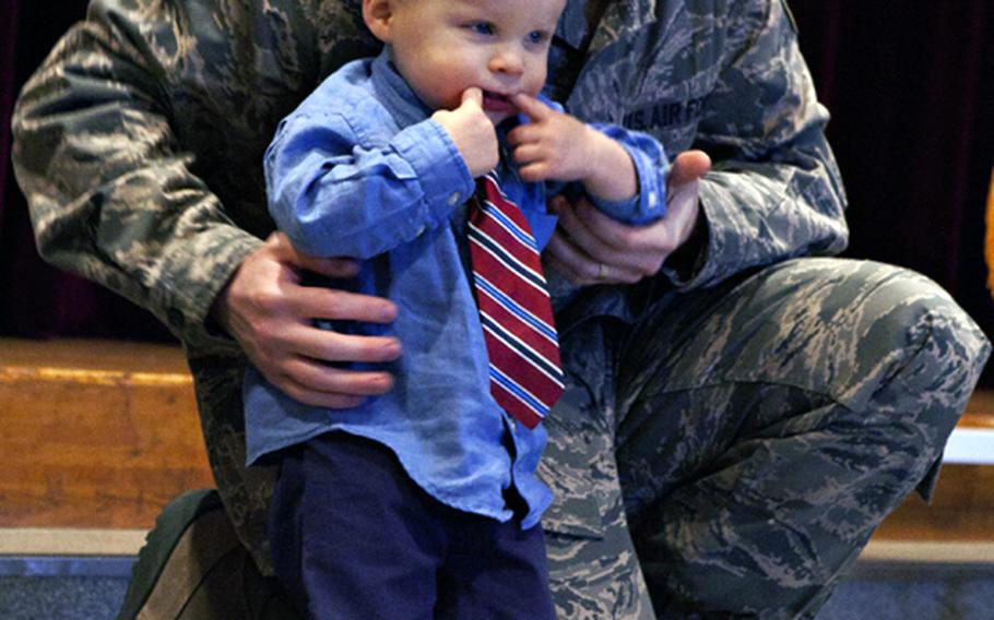 18-month-old Jonas Russell uses his fingers to make a smiley face as his father, Senior Airman Joshua Russell, 374th Communications Squadron, gives him the Home Front Hero award Feb. 11, 2011, at the Yokota Airman and Family Readiness Center.
