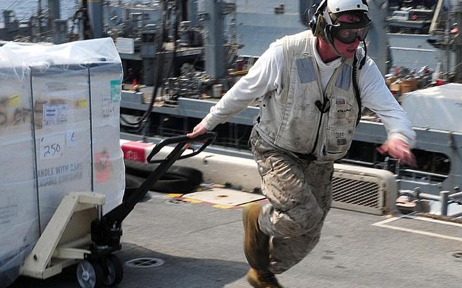 Marine Cpl. Roger Bevelhimer, assigned to the combat cargo division of the amphibious assault ship USS Essex, moves cargo on the flight deck during a vertical replenishment at sea with USNS Richard E. Byrd on Tuesday.