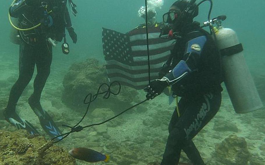 Okinawa-based Army Sgt. Juanita Tompkins, right, re-enlists underwater during a ceremony conducted Wednesday by Col. Lance. R. Koenig, left, Commander 10th Support Group and Army on Okinawa.