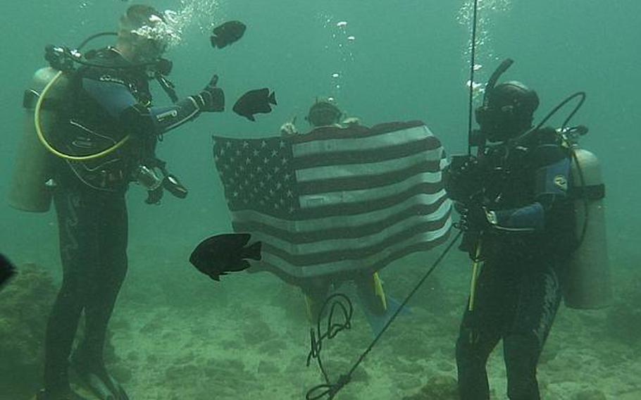 Okinawa-based Army Sgt. Juanita Tompkins, right, re-enlists underwater Wednesday in a ceremony conducted by Col. Lance. R. Koenig, left, Commander 10th Support Group and Army on Okinawa.