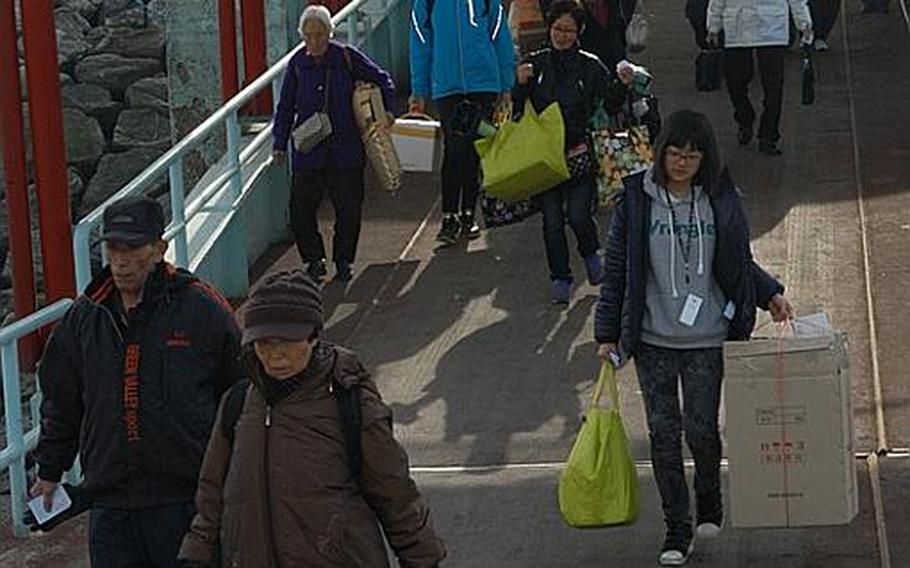 Yeonpyeong Island residents walk down a ramp toward a ferry Thursday that would take them back to their tiny South Korean fishing village on the Yellow Sea. Most of the island's residents have been living on the South Korean mainland since North Korea attacked their village on Nov. 23, killing four people.