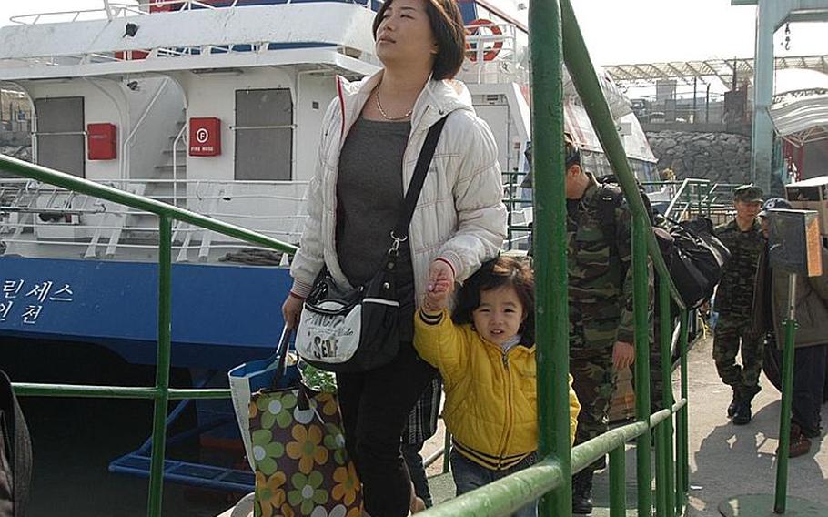 A mother and daughter board a ferry Thursday headed for South Korea's Yeonpyeong Island. Most residents of the island have lived on the South Korean mainland since North Korea launched an artillery attack on Yeonpyeong on Nov. 23. Most of the residents returned to the island this week.
