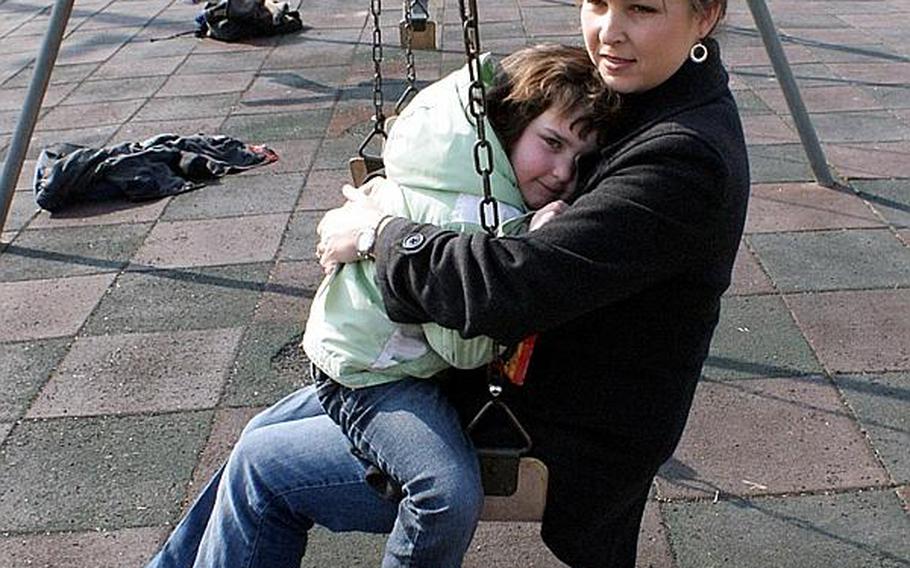 Laura Paterson, an Army spouse, holds her 5-year-old daughter, Taylor, on the swings Friday at the Seoul American Elementary School playground at Yongsan Garrison.