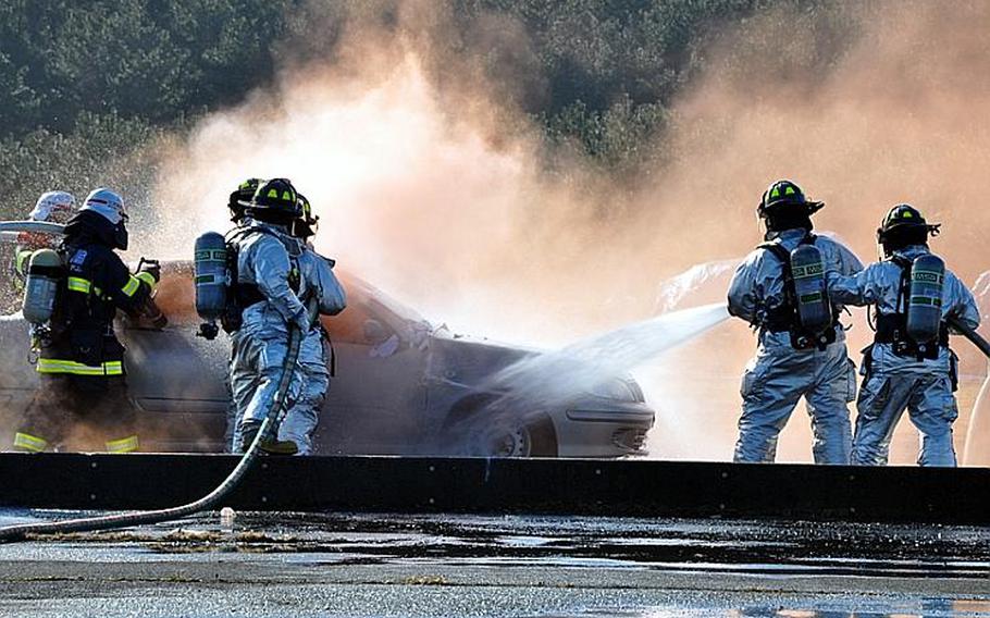 Misawa City and Misawa Air Base firefighters work to extinguish a simulated UH-60 crash Wednesday at the city port during a joint training exercise.