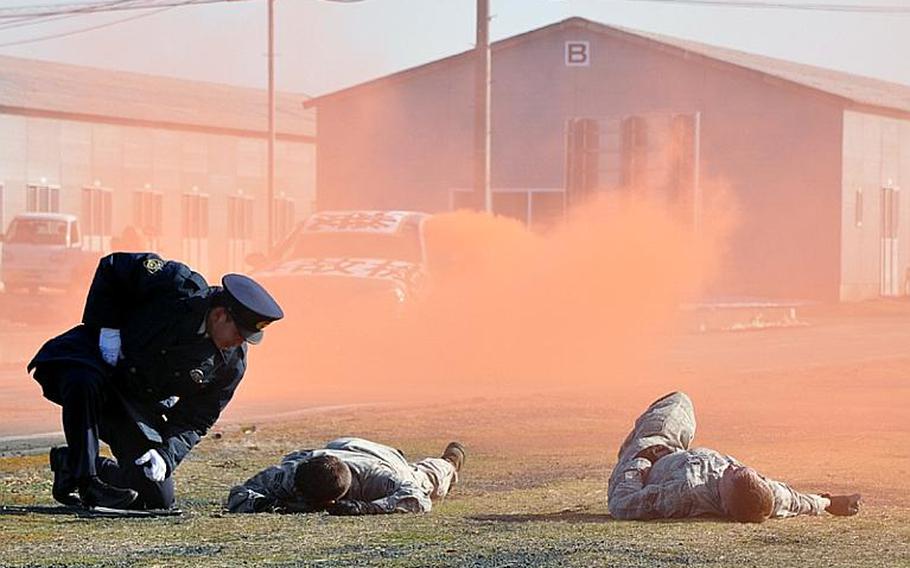A Misawa City policeman discovers two 'injured' American helicopter pilots during a training exercise Wednesday at the city port. Japanese and American officials worked to fine-tune their response to an off-base incident involving an American aircraft.