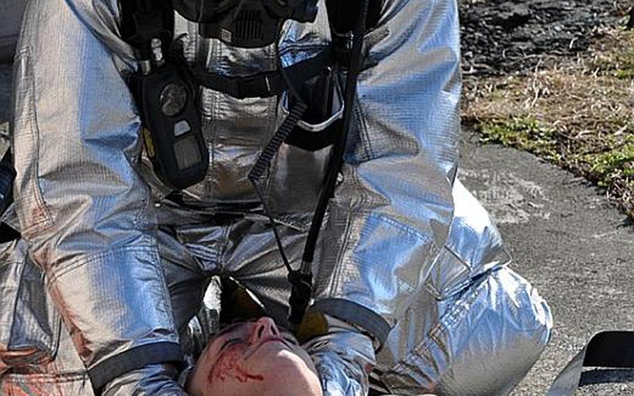 A Misawa Air Base firefighter treats Senior Airman Michael Ziemet, playing the role of an injured UH-60 pilot, during a training exercise Wednesday at the Misawa City port.