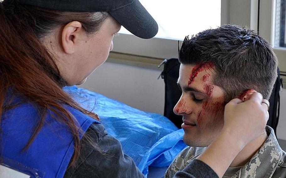 Elaine Ortiz-Harrison applies fake injuries to Senior Airman Kyle Moore on Wednesday prior to a training exercise. Japanese and American officials co-hosted the joint training exercise to fine-tune their response to an off-base incident involving an American aircraft.