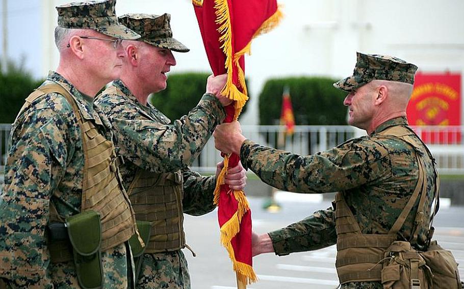 Brig. Gen. Mark A. Brilakis, center, passes 'The Fightin' Third' battle colors back to Sgt.  Maj. Bruce Cole, 3rd marine division sergeant major, right, after receiving them from the outgoing Commanding General of 3rd Marine Division, Maj. Gen. James B. Laster. Brilakis took the helm of 3rd Marine Division Tuesday in a ceremony aboard Camp Courtney on Okinawa.
