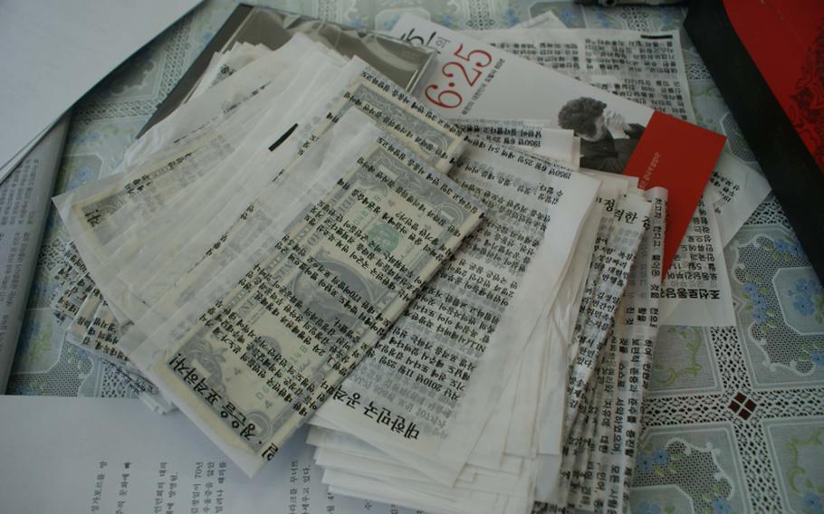 U.S. dollar bills, wrapped in plastic fliers denouncing the Kim Jong Il regime, sit on a table in the office of Fighters for Free North Korea. Underneath them is a booklet titled with the date "6.25," referencing the June 25 anniversary of the beginning of the Korean War in 1950. The dollar bills will be sent into North Korea next week inside balloons, and will help North Koreans buy rice on the black market, according to Park Sang-hak, the group&#39;s chairman. Each dollar can buy approximately four kilograms of rice, he said.