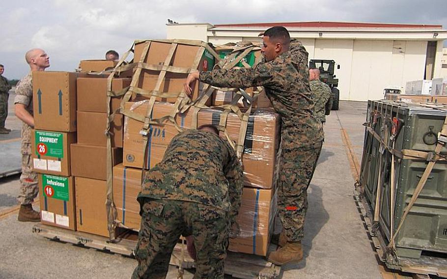 Lance Cpl. Jesse Frields, left; Cpl. Chris Vandercook, center and Cpl. Francisco Tomassini, of the Combat Logistics Regiment 37 of the 3rd Marine Logistics Group, prepare to load aid supplies Saturday at Marine Corps Air Station Futenma.