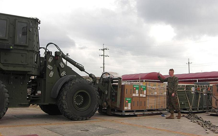 Cpl. Michael Phillips of the Combat Logistics Regiment 37 of the 3rd Marine Logistics Group guides a folklift Saturday to load relief supplies onto a KC-130J.