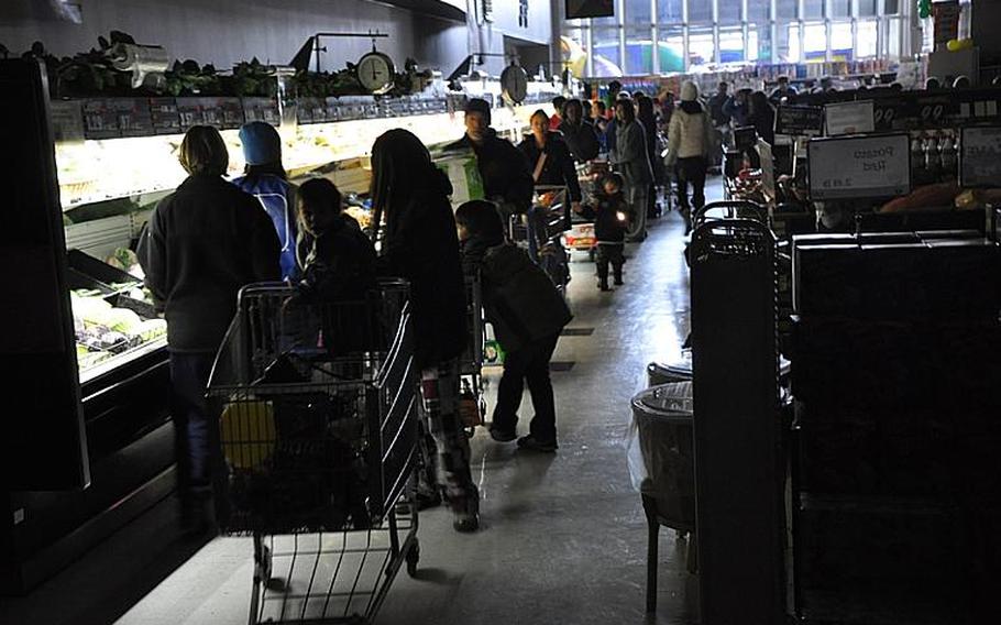 Customers at the Misawa Air Base commissary shop by the light of grocery counters Saturday.