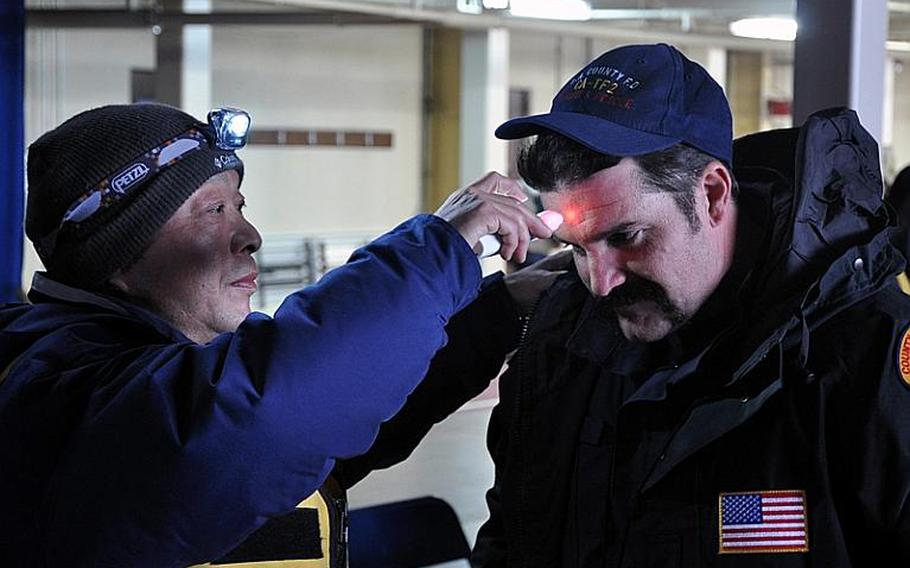 A Japanese customs official checks to see whether U.S. search-and-rescue specialist Joe Carri has a fever as Carri officially enters Japan through Misawa Air Base on Sunday.