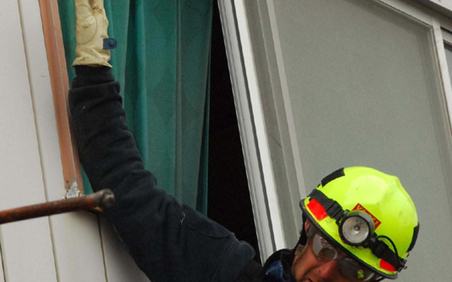 Tom Carver, rescue specialist with Fairfax County Search and Rescue, shimmies through a gap between a collapsed home's roof Tuesday in Ofunato, Japan, to search for survivors of a deadly earthquake and tsunami.