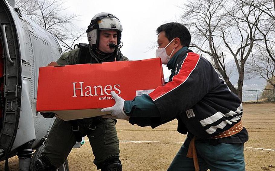 Petty Officer 2nd Class James Rivers hands a box of undershirts to a Japanese man in Ofunato city, Japan, during a humanitarian relief mission on Tuesday. Rivers and fellow Seahawk helicopter crew member Petty Officer 3rd Class Caleb Benedict unloaded thousands of pounds of supplies at sites they visited in the helo, piloted by Lt. Cmdr. Ben Van Buskirk and Lt. Victoria Throckmorton.