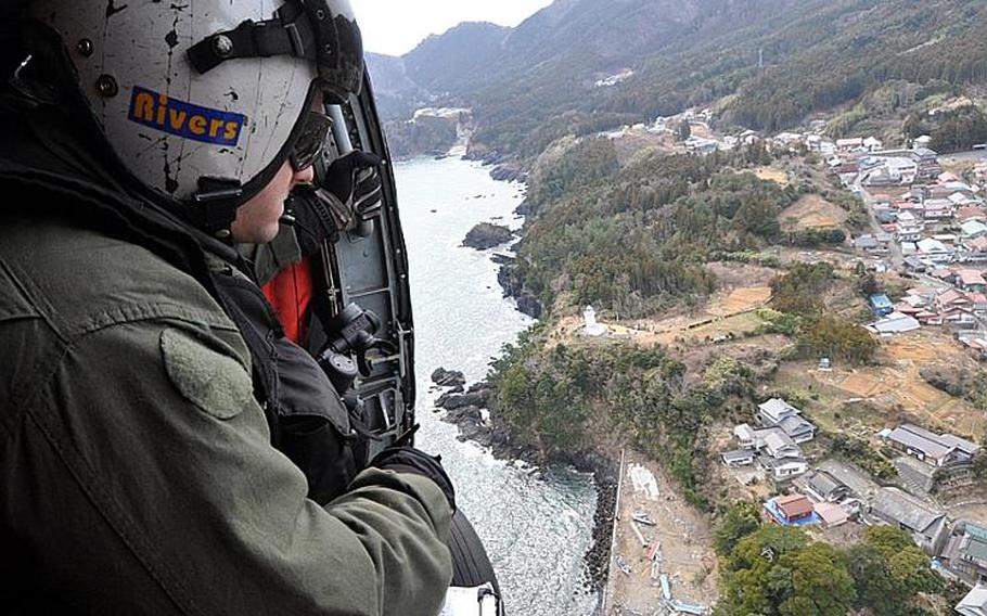 Petty Officer 2nd Class James Rivers looks out the side of a Seahawk helicopter at the tsunami damage along the coastline of northeastern Japan during a humanitarian relief supply mission in Iwate Prefecture.