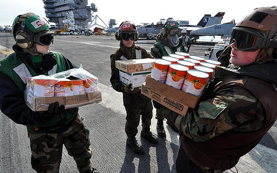 Sailors aboard USS Ronald Reagan, floating off the coast of Japan, wait to load humanitarian relief supplies Tuesday into a U.S. Navy Seahawk belonging to Helicopter Anti-Submarine Squadron 14, piloted by Lt. Cmdr. Ben Van Buskirk and Lt. Victoria Throckmorton. The pilots made several trips into tsunami-damaged towns along the coast to deliver the supplies.