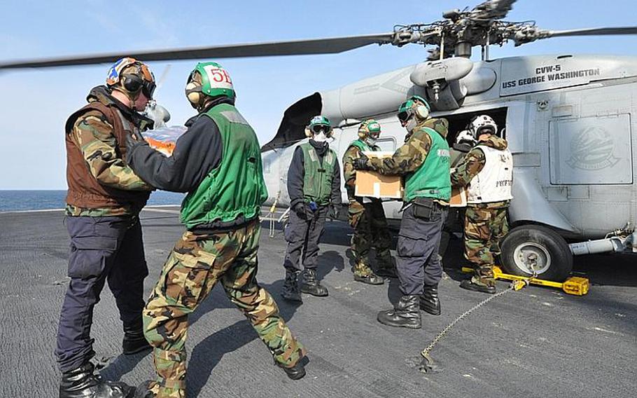 Sailors aboard USS Ronald Reagan, floating off the coast of Japan, load humanitarian relief supplies March 22, 2011, into a U.S. Navy Seahawk belonging to Helicopter Anti-Submarine Squadron 14, piloted by Lt. Cmdr. Ben Van Buskirk and Lt. Victoria Throckmorton. The pilots made several trips into tsunami-damaged towns along the coast to deliver the supplies.