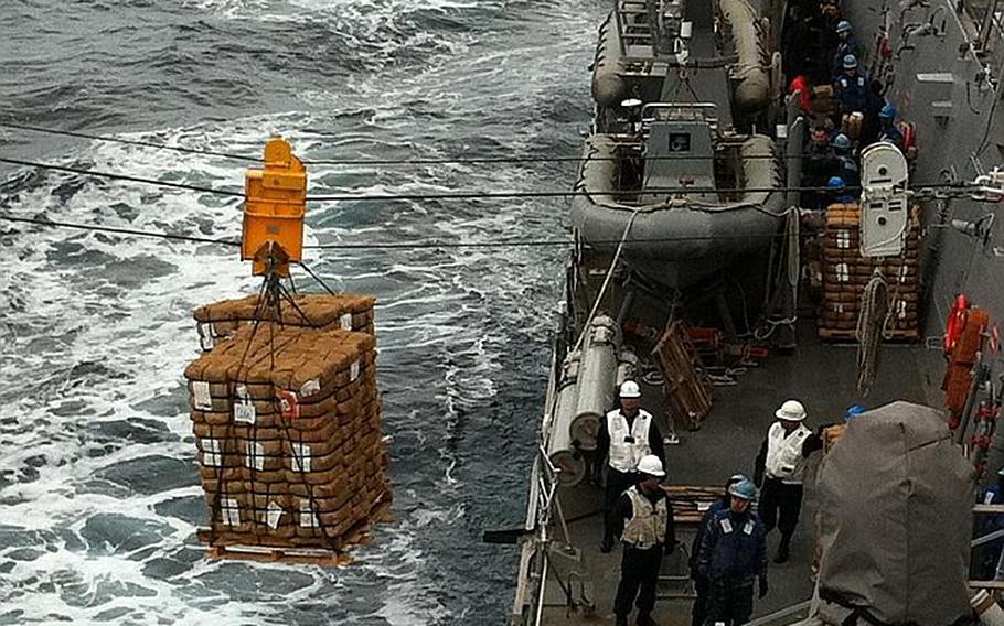 USS McCampbell crew members work to bring on humanitarian assistance and disaster relief supplies during an underway replenishment Wednesday.  The McCampbell is off the coast of Japan to provide disaster relief and humanitarian assistance to Japan in support of Operation Tomodachi.