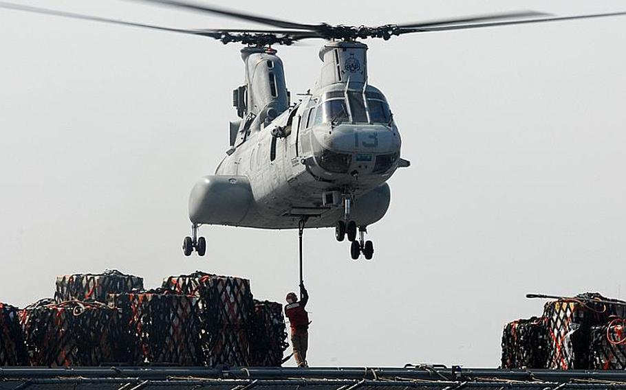 A crew member of the Military Sealift Command Dry Cargo and Ammunition ship USNS Matthew Perry attaches cargo to an CH-46E Sea Knight helicopter assigned to the &#39;Flying Tigers&#39; of Marine Medium Helicopter Squadron 262 during a vertical replenishment Tuesday. The Flying Tigers are based in Okinawa, Japan, and are conducting humanitarian assistance missions in northern Japan as part of Operation Tomodachi.