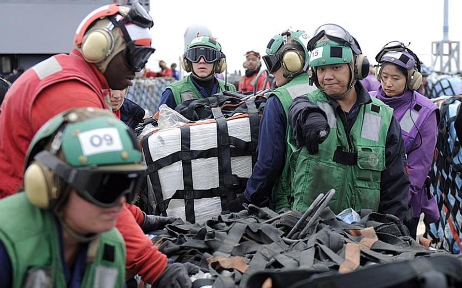 Petty Officer 2nd Class Mariano Tamandong, assigned to the 'Warlords' of Light Helicopter Antisubmarine Squadron 51, directs sailors moving pallets of humanitarian supplies aboard 7th Fleet command ship USS Blue Ridge during a vertical replenishment-at-sea with the USNS Pecos on Monday.