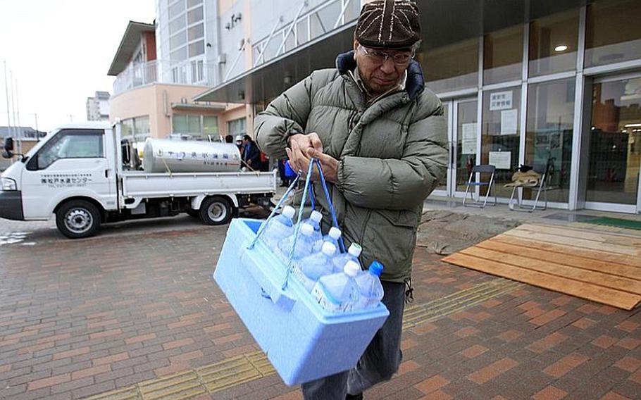 A man carries bottles of water after he got water from a supply water tank in earthquake-damaged Urayasu, Chiba prefecture, near Tokyo, Wednesday, March 23, 2011. A spike in radiation levels in Tokyo tap water spurred new fears about food safety Wednesday as rising black smoke forced another evacuation of workers trying to stabilize Japan's radiation-leaking nuclear plant.