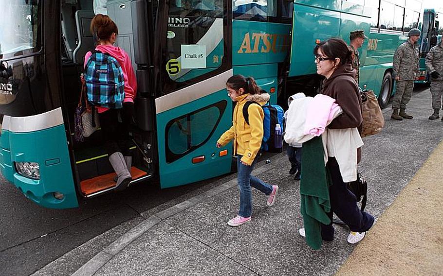 Camp Zama families board buses at the Taiyo Community Center on Yokota Air Base on Friday, en route to the passenger terminal on base.