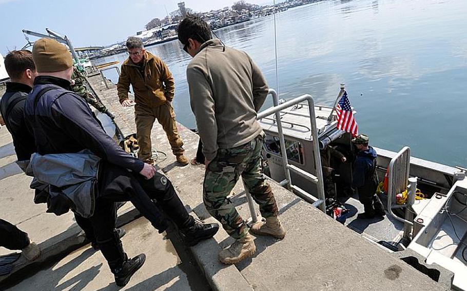 U.S. Navy divers discuss how to best survey the Hachinohe City port on Friday.